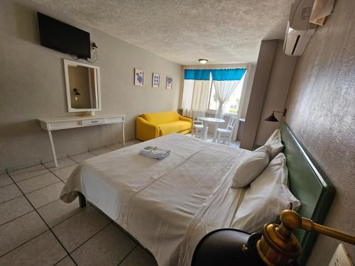 a bedroom with a bed and a living room at Hotel Punto Poza Rica in Poza Rica de Hidalgo