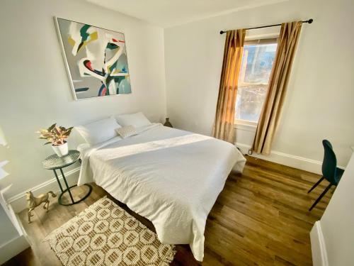 1 dormitorio con cama blanca y ventana en Lakes Region Gem - Chic Victorian Apt - Laconia, en Laconia