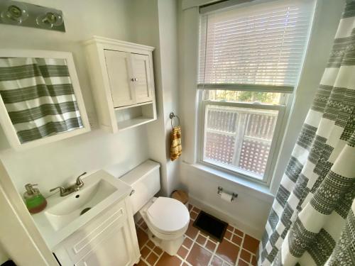 bagno con servizi igienici, lavandino e finestra di Lakes Region Gem - Chic Victorian Apt - Laconia a Laconia