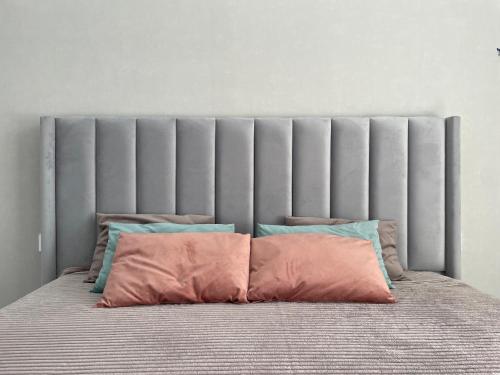 een bed met een grijs hoofdeinde met drie kussens bij Sat City Deluxe in Astana