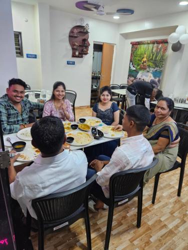 a group of people sitting around a table eating food at Hotel Sai Dakshina Inn & The Fern Restaurant in Shirdi