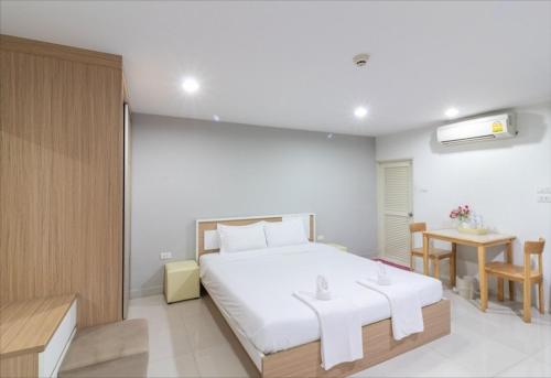 Un dormitorio con una gran cama blanca y una mesa en Siam Privi Hotel, en Bangkok