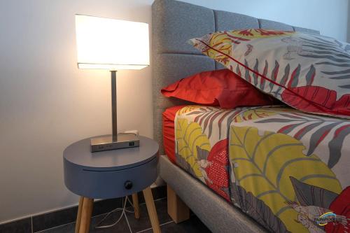 a lamp on a table next to a bed at L'Anse Plage appartement 2 chambres avec spa à 200 m de la plage, jardin Privé et Parking in Les Trois-Îlets