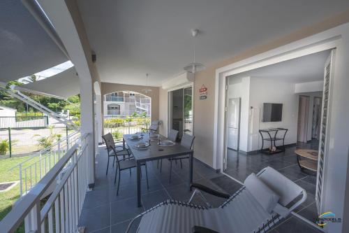 a dining room with a table and chairs on a balcony at L'Anse Plage appartement 2 chambres avec spa à 200 m de la plage, jardin Privé et Parking in Les Trois-Îlets