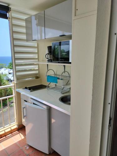 a white kitchen with a sink and a window at Appartements vue mer - Résidence de la baie - Tartane in La Trinité