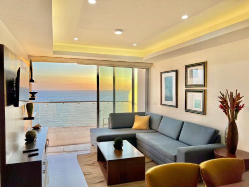 a living room with a blue couch and a view of the ocean at Sunset View Malecón 1402 Vista panoramica al mar in Mazatlán