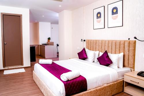 1 dormitorio con 1 cama grande con almohadas moradas en Casa Hotel & Suites, Gachibowli, Hyderabad en Hyderabad