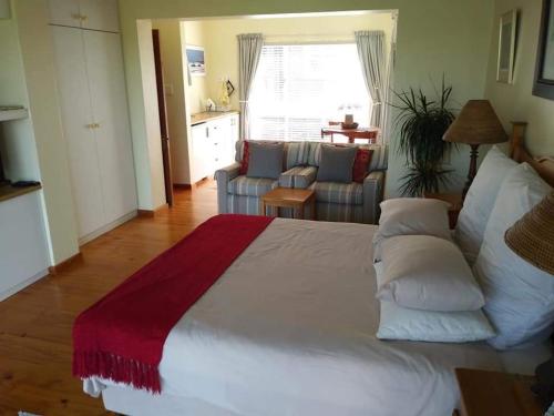 a bedroom with a large white bed and a living room at Oppikrom Rivertide 36 in St Francis Bay