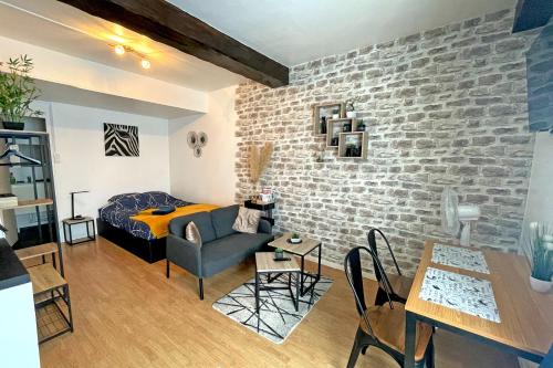 a living room with a brick wall and a bedroom at Escapade Moretaine - Cosy Studio in Moret-sur-Loing