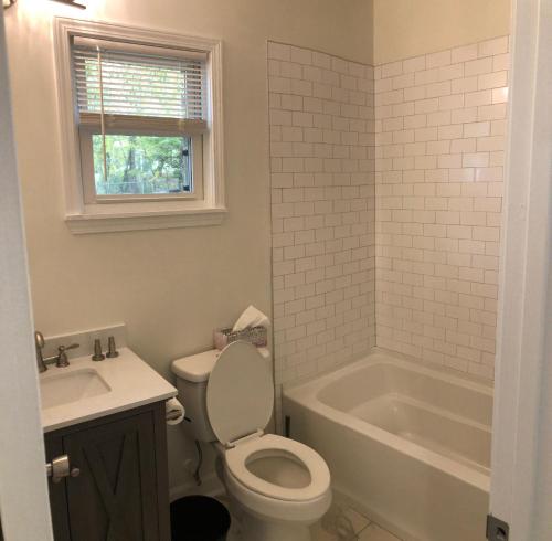 a bathroom with a toilet and a tub and a sink at Lakewoodlyon Park Renovated Cottage Near Duke 23a in Durham