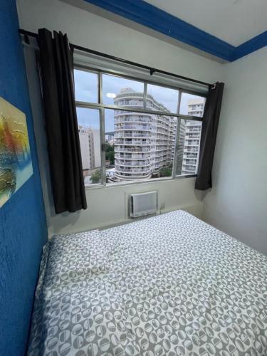 um quarto com uma cama e uma grande janela em Apartamento na Zona Sul Carioca no Rio de Janeiro