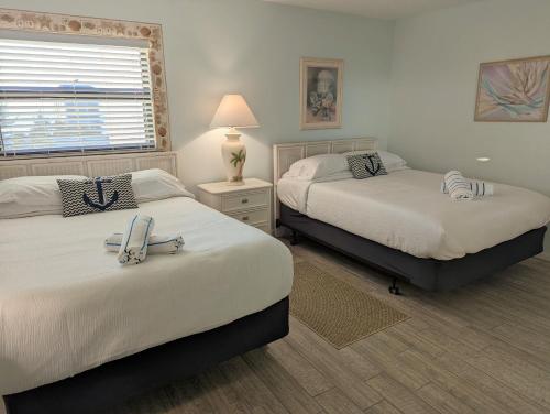 a bedroom with two beds and a lamp and a window at Sea Club Condo #405 in Clearwater Beach