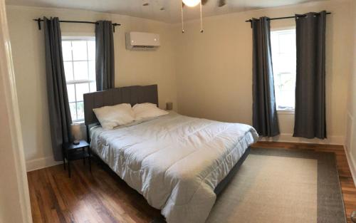- une chambre avec un lit et 2 fenêtres dans l'établissement Renovated Cottage Minutes From Downtown, à Durham