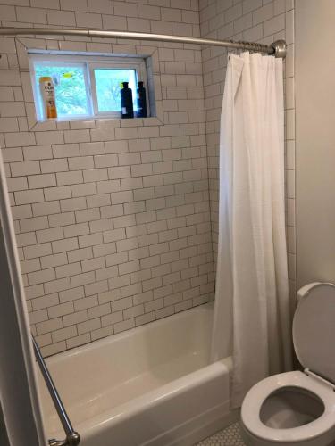 a bathroom with a white tub and a toilet at Renovated Space Close To Downtown - A in Durham