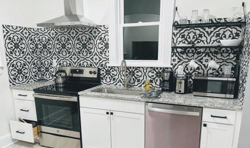 a kitchen with white cabinets and a black and white wallpaper at Renovated 1 Bedroom In Forest Hills - A in Durham