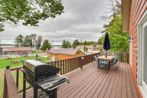 a wooden deck with a grill and a table with chairs at Charming Curtis House Large Deck with Lake View! in Curtis