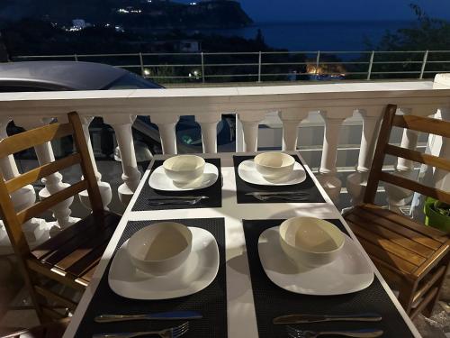 a table with plates and hats on a balcony at Lazaris kwstas Rooms in Himare