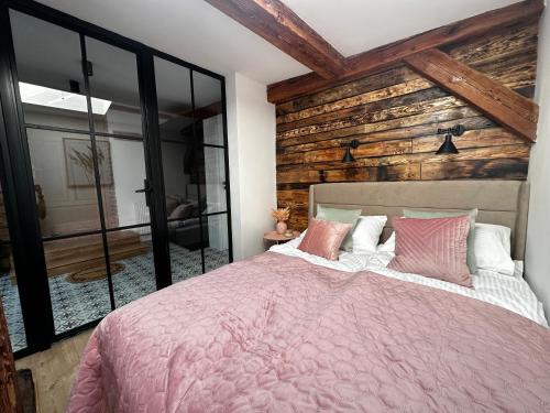 ein Schlafzimmer mit einem rosa Bett und einer Holzwand in der Unterkunft Apartament Miodowy - DARMOWY PARKING - KlMATYZACJA - WIFI in Toruń
