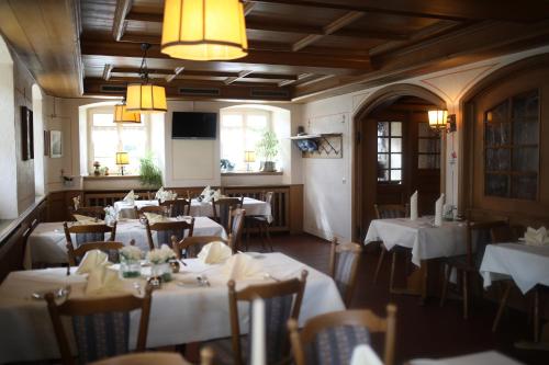 ein Restaurant mit Tischen und Stühlen mit weißem Tischtuch in der Unterkunft Gasthaus Hotel zum Kreuz in Stetten am Kalten Markt