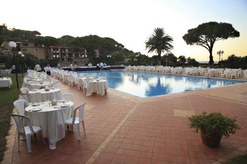 a large pool with tables and white tables and chairs at Hotel Desiree in Procchio
