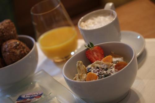 a table with three bowls of cereal and a glass of orange juice at Gasthaus Hotel zum Kreuz in Stetten am Kalten Markt