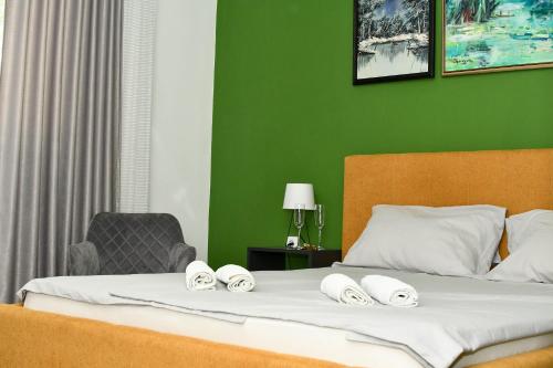 a bedroom with a bed with a green wall at Apartman Centar in Sombor