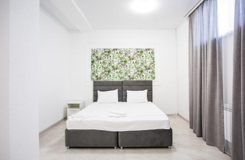a white bedroom with a bed and a window at Domus Hotel in Aktau