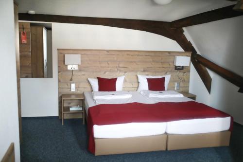 a bedroom with a large bed with red and white pillows at Gasthaus Hotel zum Kreuz in Stetten am Kalten Markt