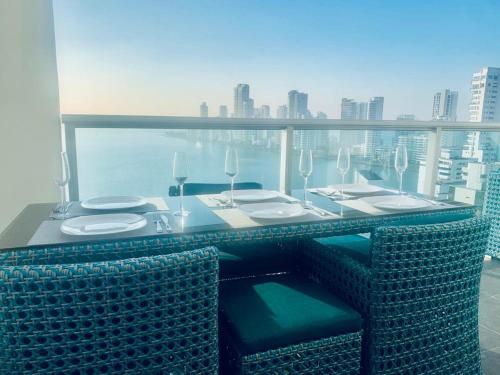 a table with chairs and wine glasses on a balcony at 19TH FLOOR LUXURY APARTMENT BAY VIEW CARTAGENA in Cartagena de Indias
