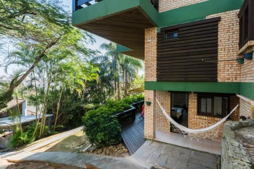 a brick house with a green roof and trees at Pousada Albacora in Bombinhas