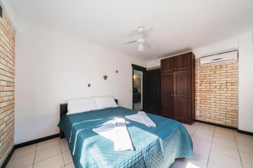 a bedroom with a bed with a blue blanket at Pousada Albacora in Bombinhas