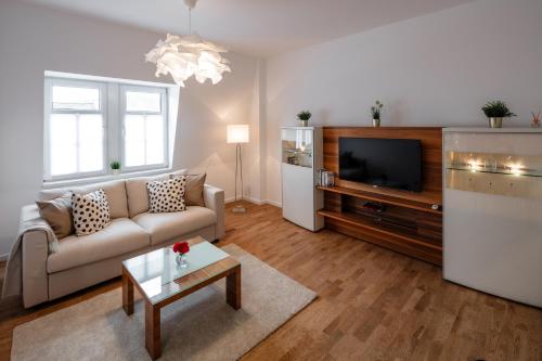 a living room with a couch and a tv at Goethe Palais Suite Zauberlehrling 4P l Lift l Parkplatz in Aue