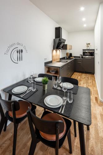 a dining room with a black table and chairs at Goethe Palais Suite Zauberlehrling 4P l Lift l Parkplatz I Zentrum I Helios in Aue