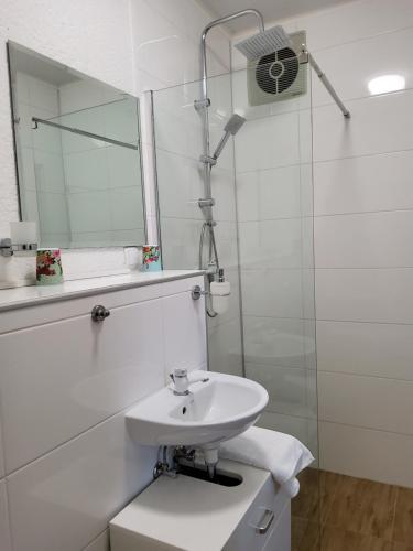 a white bathroom with a sink and a mirror at Gästehaus Schönstein in Gilserberg
