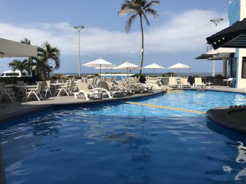 a swimming pool with chairs and umbrellas at Olas Altas Inn Hotel & Spa in Mazatl&aacute;n