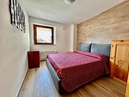 a bedroom with a bed with a red comforter at Nido Del Cervino - Ingresso Indipendente in Valtournenche