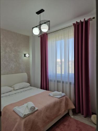 a bedroom with a bed and a window with red curtains at Apartament Rezidențial in Suceava