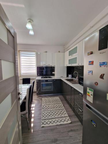 cocina con armarios blancos, mesa y sillas en Apartament Rezidențial, en Suceava