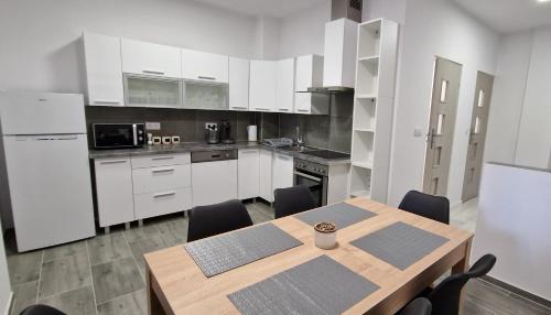 a kitchen with a wooden table and white cabinets at Apartament Agat in Lwówek Śląski