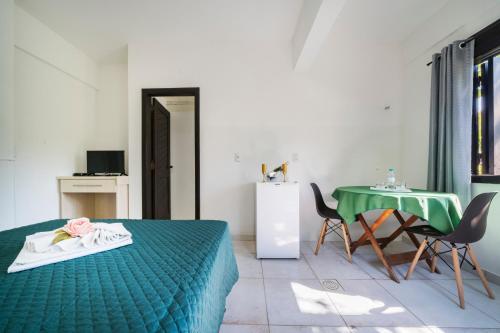 a bedroom with a green bed and a table and chairs at Pousada Albacora in Bombinhas