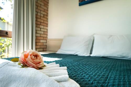 a bedroom with a bed with towels and a flower on it at Pousada Albacora in Bombinhas