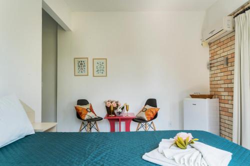 a bedroom with a bed with a blue blanket and chairs at Pousada Albacora in Bombinhas