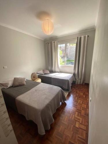 a bedroom with two beds and a window at Residência Azevedo in Câmara de Lobos