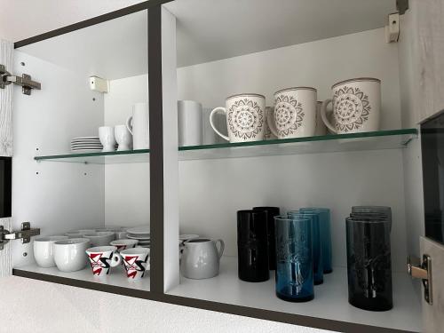 a shelf with cups and vases on it at Giulia Ferienwohnung - Zentral in Tuttlingen