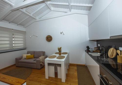 a kitchen and living room with a table and a couch at Casa do Brasão in Lajes do Pico