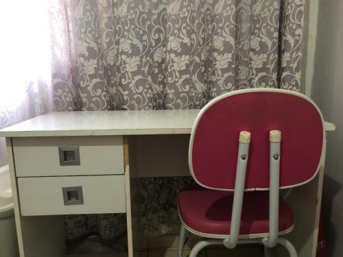 - un bureau avec une chaise rouge à côté d'un rideau dans l'établissement Residencial Parque da Liberdade IV, à Sao Jose do Rio Preto