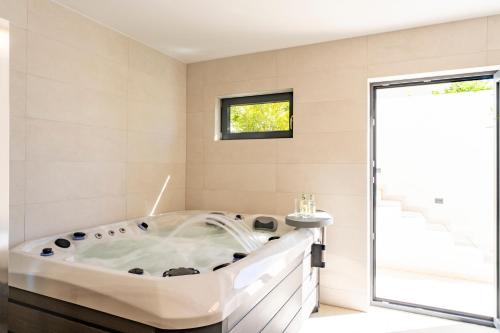 una vasca bianca in un bagno con finestra di Villa Infinity View a Primošten