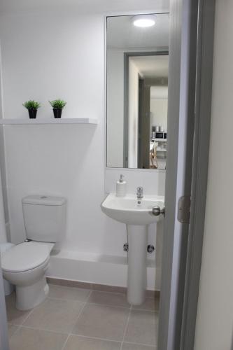 a white bathroom with a toilet and a sink at Lindo departamento vista al mar in Coquimbo