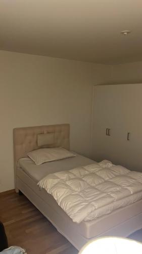 uma cama branca num quarto com uma parede branca em Hyllie em Malmo