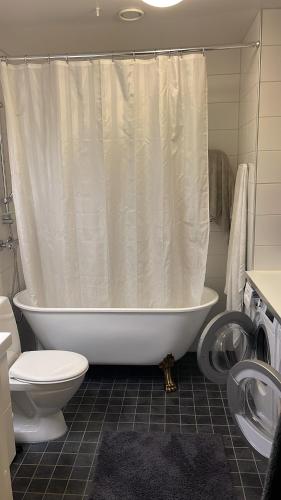 uma casa de banho com uma cortina de chuveiro branca e um WC. em Hyllie em Malmo